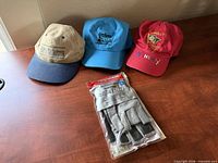 Overview of three caps and packaged sailing gloves on desk