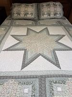 Bed showing full quilt with star motif and both pillow shams