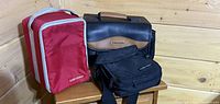 Three storage cases displayed on wooden stool: red Case Logic bag, black Trikon camera bag, black Case Logic pouch