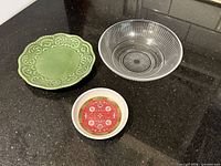 Overview of three dishes: green ceramic plate, clear ribbed glass bowl, red Thunder Group sauce plate