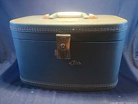 Front view of teal Flite train case showing handle, latch and logo