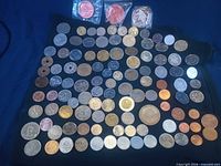 Wide view of entire lot showing over 100 assorted coins and three sealed medallions