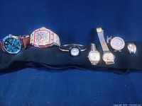 Group of seven wrist watches displayed