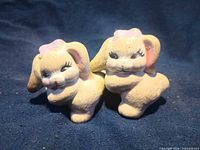 Front view of both rabbit figurines showing color, bows, facial details