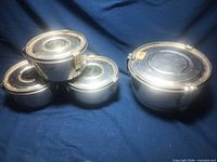 four closed stainless steel canisters grouped on blue cloth