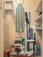 Overall view showing ironing board, ladder, cleaning tools, fluorescent lights and dusters