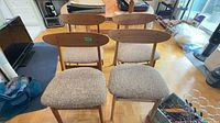 Front view of four wooden dining chairs with upholstered seats