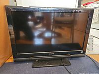 Front view of Sony Bravia 32-inch TV on stand with screen off