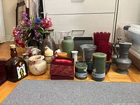 Group shot showing vases, candles, floral arrangement and assorted containers on floor