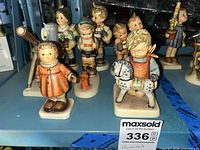 Group view of eight Goebel Hummel figurines on shelf