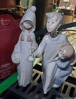 Two Lladro figurines side by side, Boy & Girl with Candle and Shepherdess with Candle