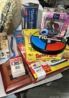 Group shot of all items stacked showing Simon, Smart Ass, Q-Fig, Don't Quote Me, Bicycle cards