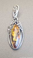 Front view of amber pendant showing leaf and vine silver setting