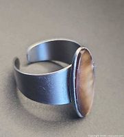 oblique view of ring showing wide adjustable cuff band and oval cabochon