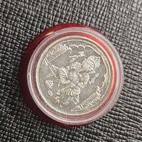 Front view of silver token showing Lord Ganesha inside capsule