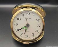 Front view of open Bulova travel alarm clock showing dial and cover