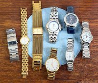 Group shot of all eight wristwatches arranged on wood surface