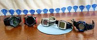 Five digital wristwatches lined up on table