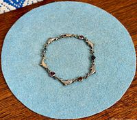 Full view of the sterling silver bracelet laid in a circle showing dolphin links and multicolour stones