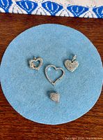 All four Swarovski heart pendants displayed on blue felt