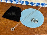 Necklace, earrings, and pouch laid out on wood surface