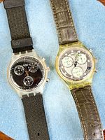 Both Swatch chronograph watches side by side showing dials and straps