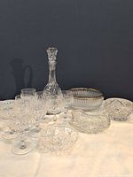 Group view of all glass pieces including decanter, eight glasses, bowls, and dish