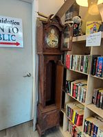 Full view of wood longcase clock beside bookshelf