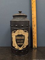 Front view showing Johnson & Bru label, lid, ruler for height reference