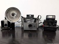 Front view of all three cameras showing models and flash attachments