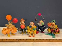 Front view of all five clown figurines lined up with ruler for scale
