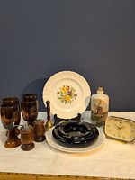 Group shot of all items: goblets, plate, ashtrays, shakers, bell, bottle, clock