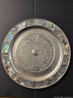 Front view of pewter wall plate showing full design and abalone rim