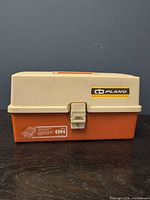 Closed Plano 4804 tackle box, orange base, beige lid, front latch and logo visible