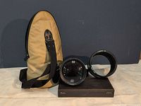 Lens, hood, case and cap displayed together