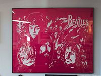 Full view of framed red/magenta Beatles silkscreen poster behind glass