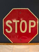 Front view of worn vintage steel stop sign with ruler for scale