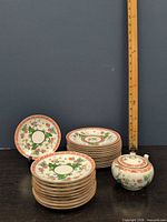 Stacks of saucers and covered sugar bowl with ruler for scale