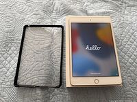 iPad front powered on beside case and box