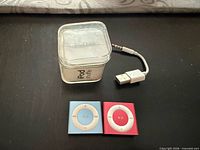 Two iPod Shuffles, clear box, USB cable overview