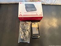 Front view of LG GR500R phone beside sealed headset and retail box