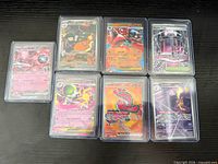 Seven full-art Pokémon cards in individual rigid plastic sleeves displayed on tabletop