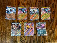 Seven Pokémon promo EX cards arranged on wood surface
