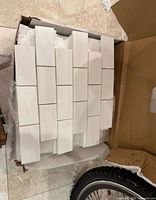 Box containing unused white marble backsplash tile sheets on mesh backing