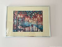 Framed puzzle showing colorful park scene, aluminum frame, beige mat, landscape orientation