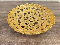 Angled view of gold metal bowl showing floral cutout pattern and texture