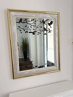 Front view of rectangular mirror with metal frame and bird design