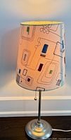 Lamp lit showing metal base, pull chain, patterned fabric shade