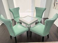 Set of four mint green dining chairs around small table