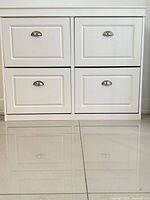 Front view of white cabinet showing four compartment doors with metal pulls